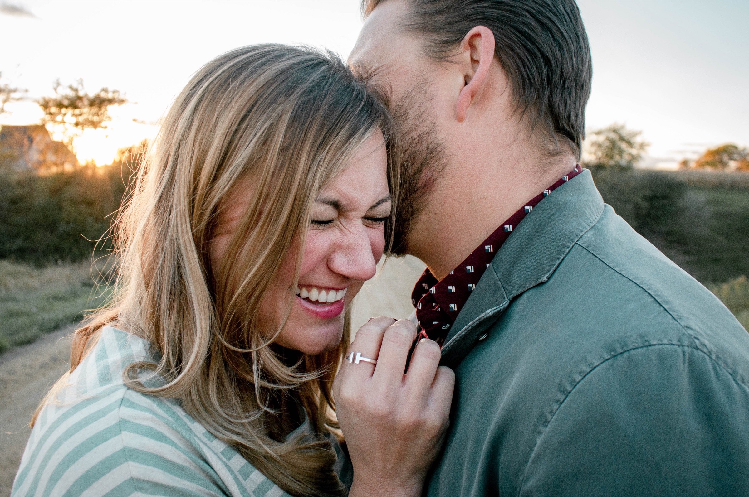 A man and a woman laughing together outdoors at sunset