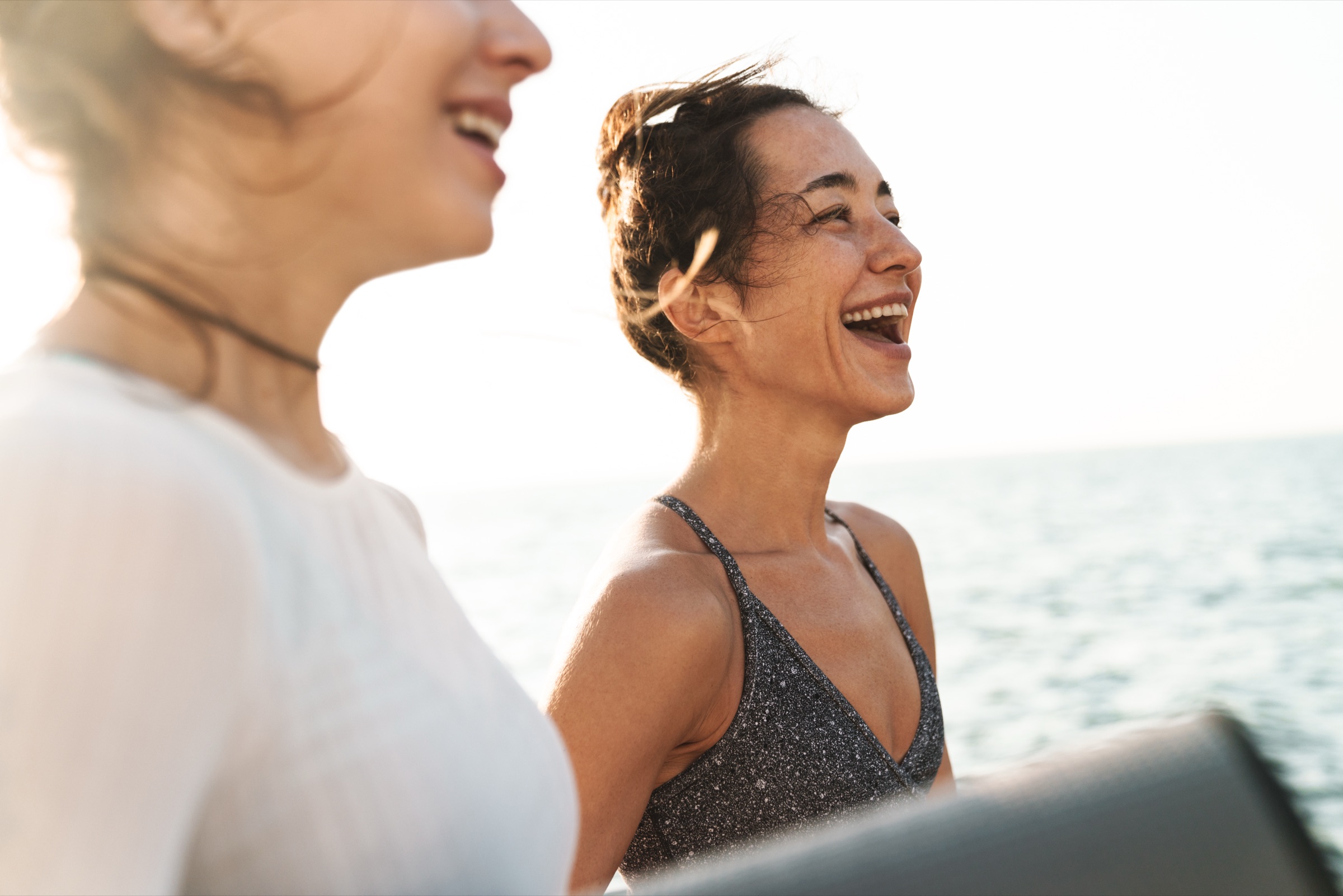 Two women laughing together by the sea